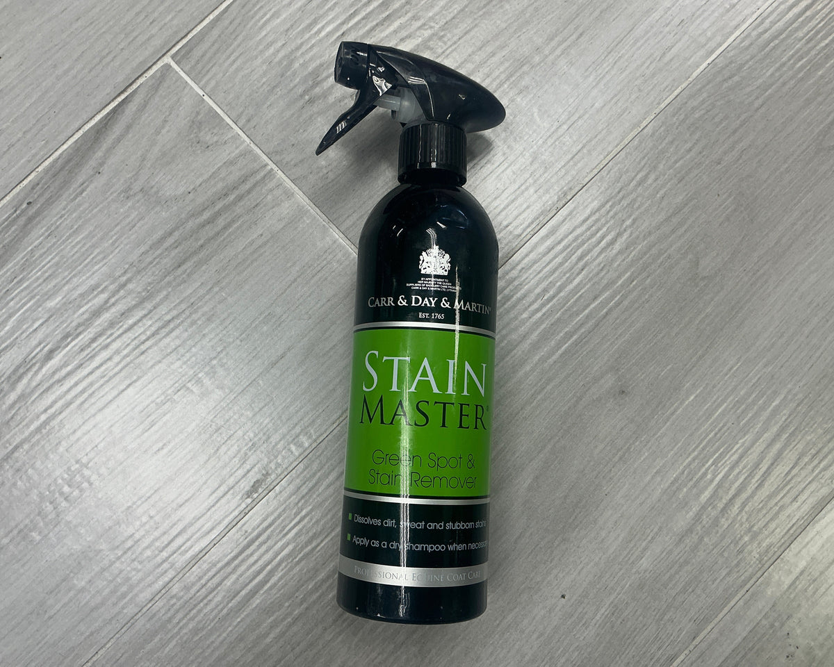 A bottle of Care & Day & Master Stain Master Stain Remover spray, featuring a black trigger sprayer and a green label, placed on a gray wood-look floor.