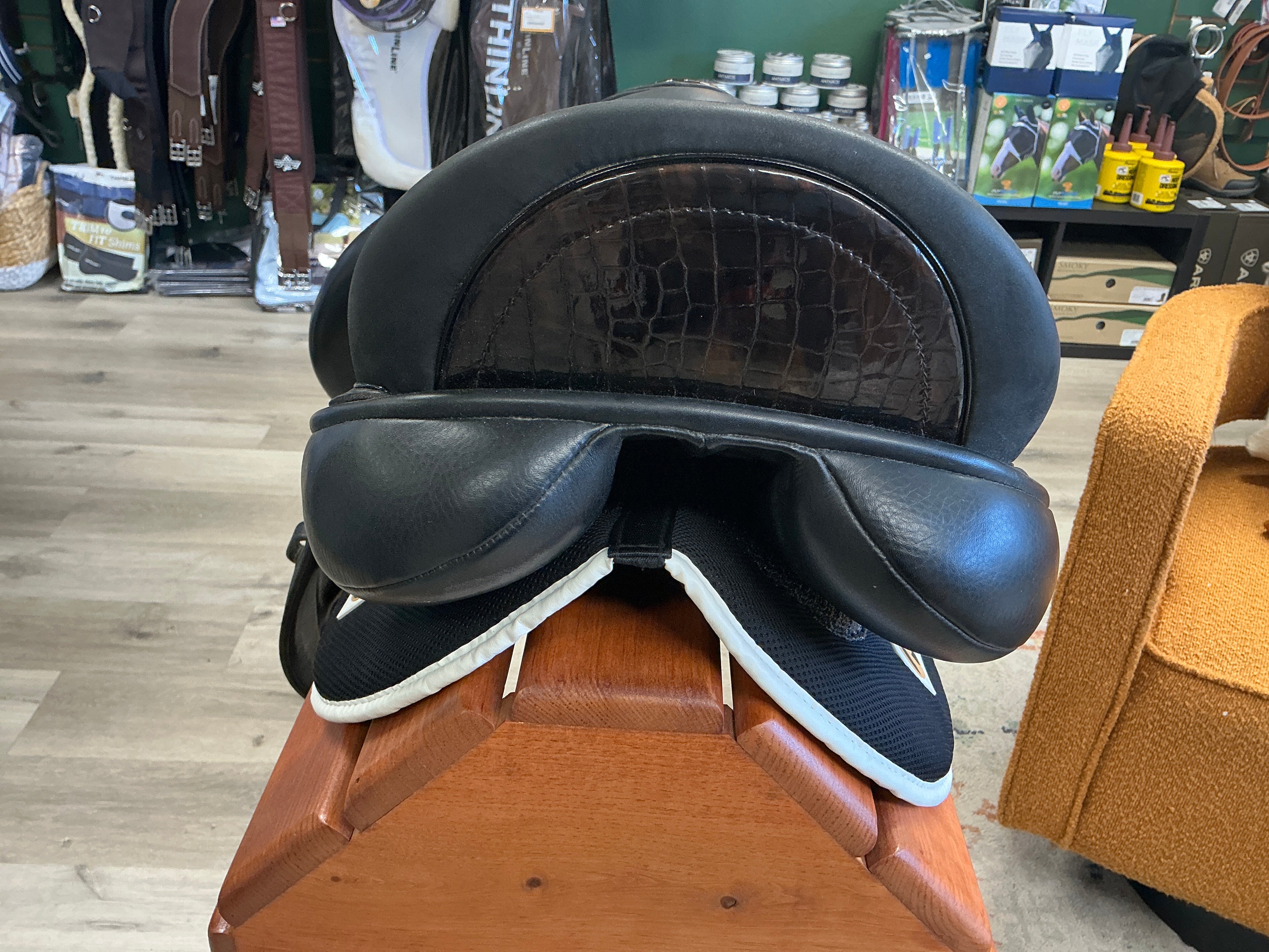 Black leather Custom Dressage saddle on a wooden stand in a store setting